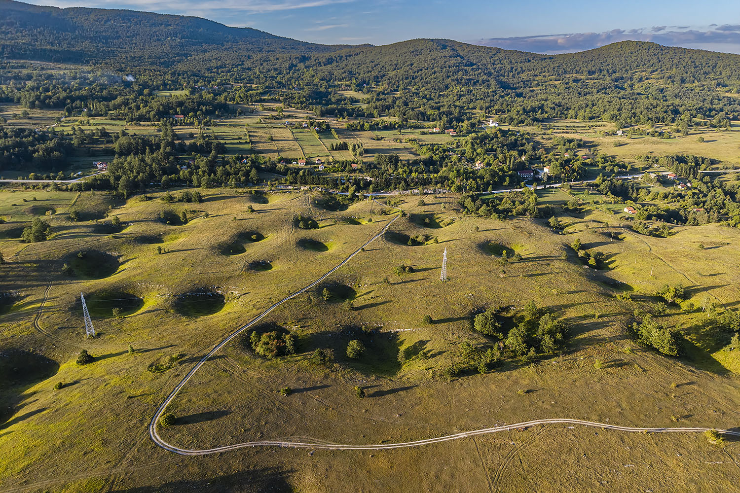Bravsko polje je visoka kraška planota med Bosanskim Petrovcem in Ključem. Vhod v brezno Jojkinovac je nad gozdnim robom na sredini fotografije. Foto Marko Pršina